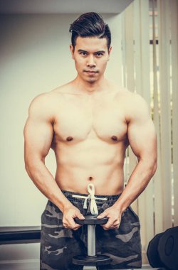 Kaslı adam vücut geliştirmeci dumbbells ile eğitim.