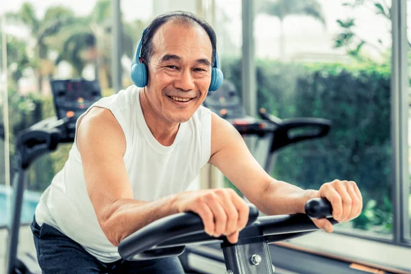 Senior man oefening op fiets machine in fitnesscentrum — Stockfoto