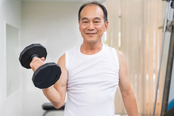 Uomo anziano che solleva manubri in palestra fitness . — Foto Stock