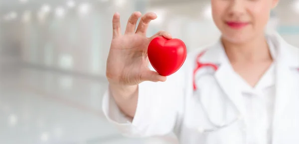 Hastane ofisinde kırmızı kalp tutan doktor. — Stok fotoğraf