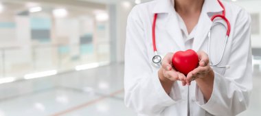 Hastane ofisinde kırmızı kalp tutan doktor.