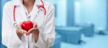 Hastane ofisinde kırmızı kalp tutan doktor.