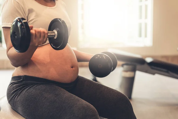 Active pregnant woman exercise in fitness center. Royalty Free Stock Photos