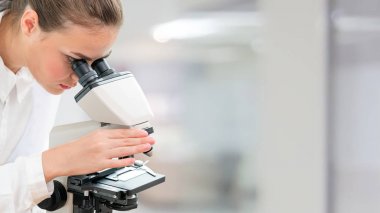 Bilim adamı araştırmacı laboratuvarda mikroskop kullanır