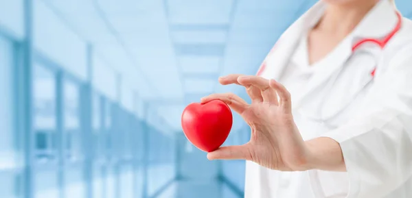 Médecin tenant un cœur rouge au bureau de l'hôpital . — Photo