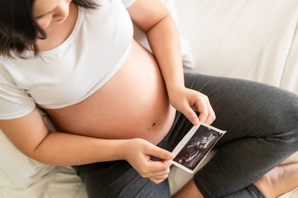 Mujer embarazada feliz y esperando un bebé en casa. — Foto de Stock