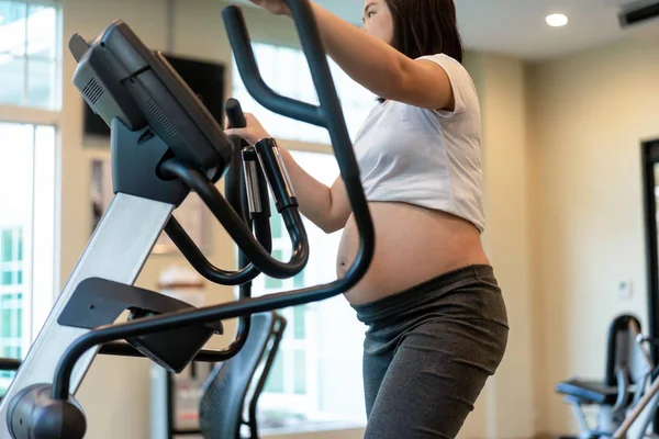 Active pregnant woman exercise in fitness center.