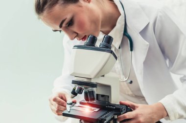 Hastane laboratuvarında mikroskop kullanan doktor.