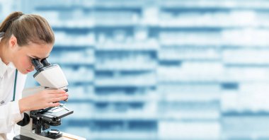 Bilim adamı araştırmacı laboratuvarda mikroskop kullanır