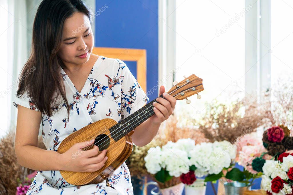 Happy woman musician playing ukulele in studio.