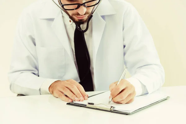 Arzt im Krankenhaus schreibt auf ein Papierdokument. — Stockfoto