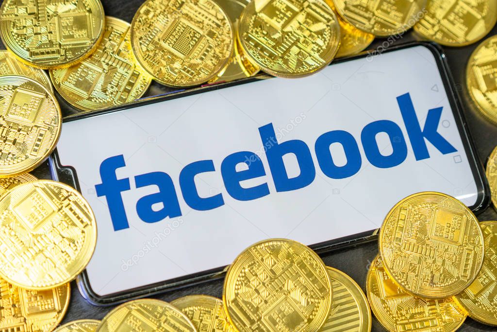 Bangkok, Thailand - July 2, 2019: Phone with Facebook logo on screen is placed with golden coins. Facebook reported to utilize new cryptocurrency called Libra expected to be used on Facebook.
