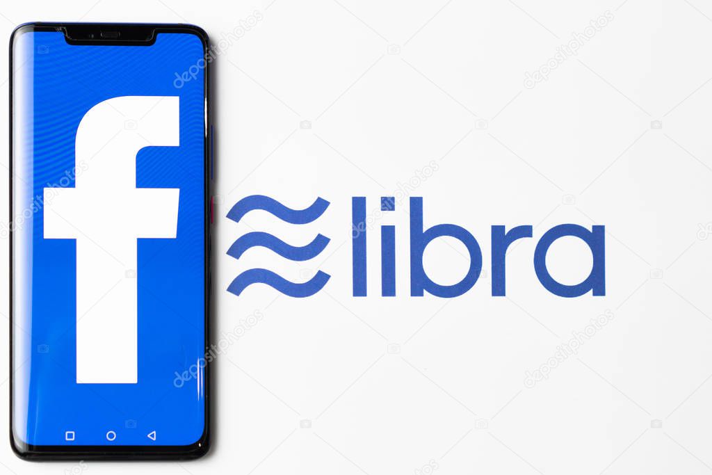 Bangkok, Thailand - July 2, 2019: Phone with Facebook logo on screen is placed on paper with Libra logo. Facebook reported to utilize new cryptocurrency called Libra expected to be used on Facebook.