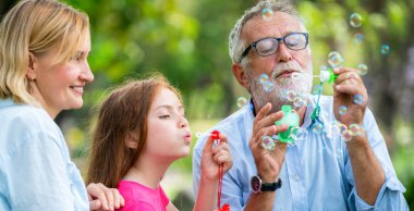 Mutlu aile parkta sabun kabarcıkları üfleme.