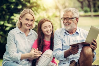 Kamu parkta dizüstü bilgisayar kullanarak Mutlu aile.