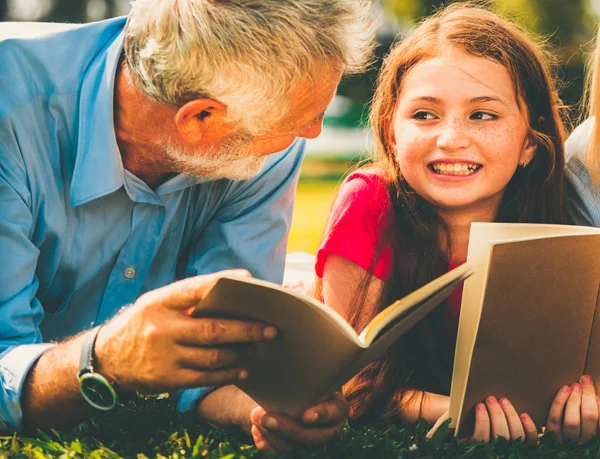 Familia feliz leer libros juntos en el jardín del parque . —  Fotos de Stock