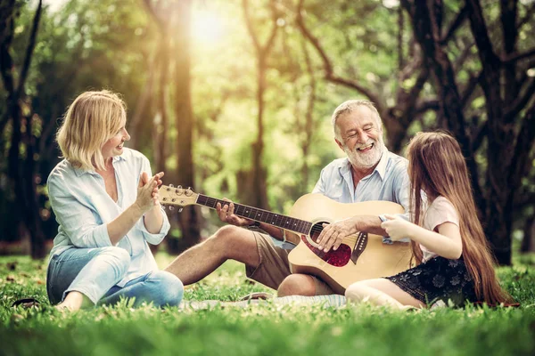 Família feliz tocar guitarra e cantar juntos no parque — Fotografia de Stock