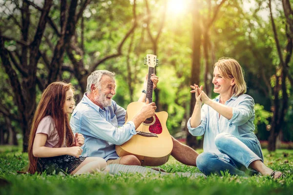 Familia feliz tocar la guitarra y cantar juntos en el parque — Foto de Stock