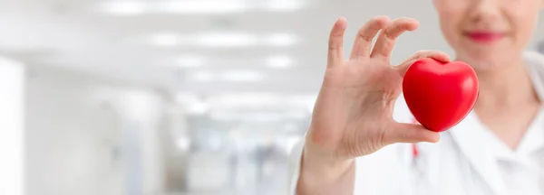 Doctor sosteniendo un corazón rojo en la oficina del hospital . — Foto de Stock