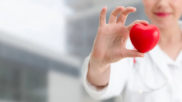 Doctor sosteniendo un corazón rojo en la oficina del hospital . —  Fotos de Stock