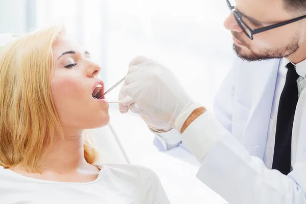 Young dentist examining patient in dental clinic. — Stock Photo, Image