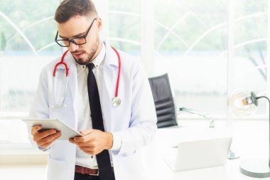 Hastanede tablet bilgisayar üzerinde çalışan doktor.