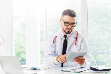 Hastanede tablet bilgisayar üzerinde çalışan doktor.