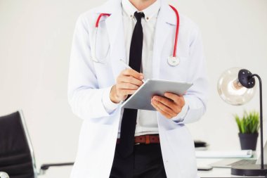 Hastanede tablet bilgisayar üzerinde çalışan doktor.