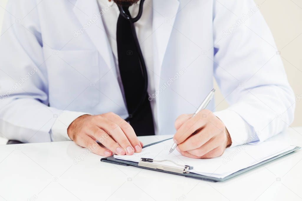 Doctor in hospital writing on a paper document.