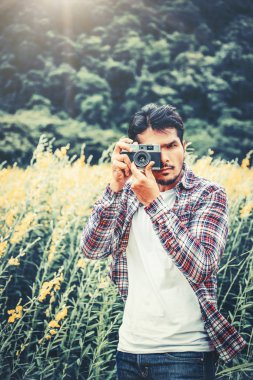 Genç hipster adam retro kamera ile fotoğraf çekmek.