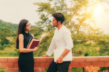 Üniversitede kitap ve dizüstü bilgisayar sohbeti olan öğrenciler.