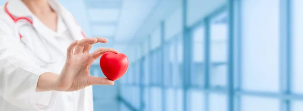 Doctor sosteniendo un corazón rojo en la oficina del hospital . — Foto de Stock