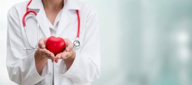Hastane ofisinde kırmızı kalp tutan doktor.