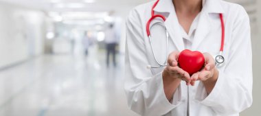 Hastane ofisinde kırmızı kalp tutan doktor.