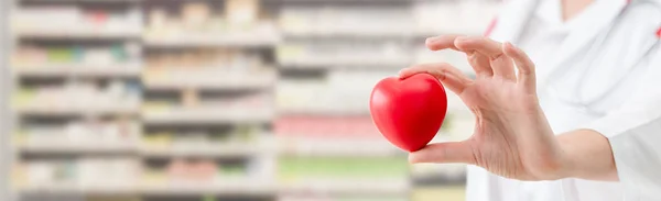 Doctor sosteniendo un corazón rojo en la oficina del hospital . — Foto de Stock