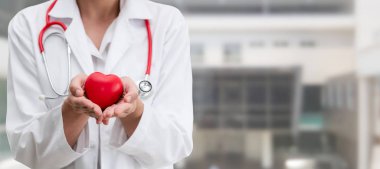 Hastane ofisinde kırmızı kalp tutan doktor.