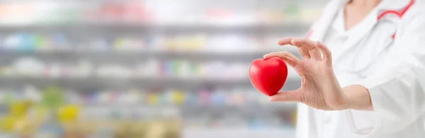 Doctor sosteniendo un corazón rojo en la oficina del hospital . — Foto de Stock