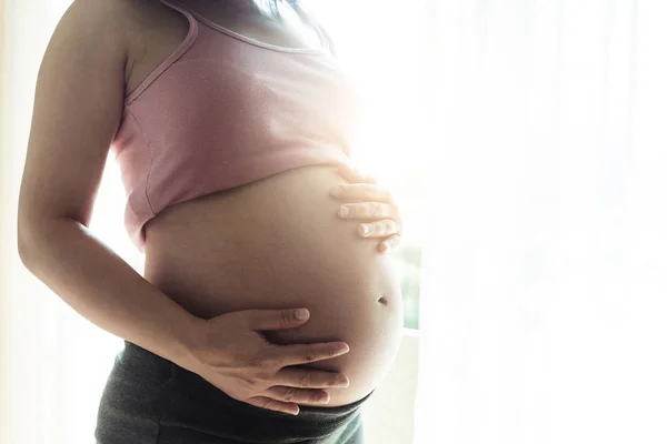 Mujer embarazada feliz y esperando un bebé en casa. — Foto de Stock