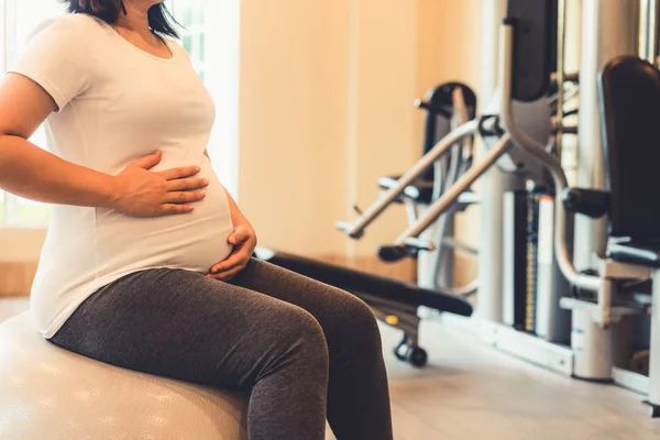 Active pregnant woman exercise in fitness center.