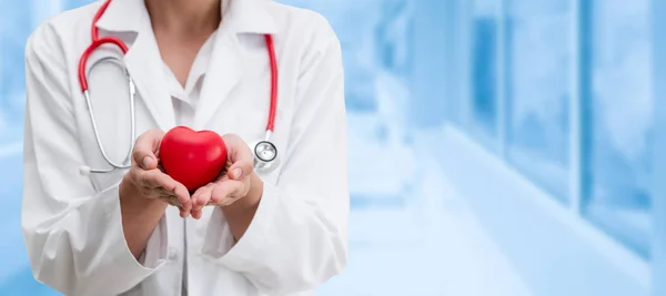 Doctor sosteniendo un corazón rojo en la oficina del hospital . — Foto de Stock