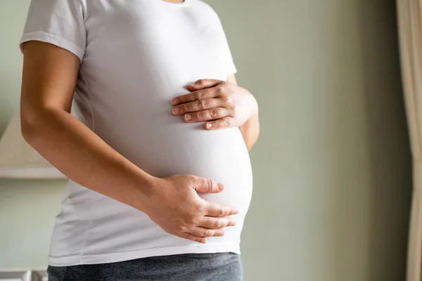 Счастливая беременная женщина и ожидающий ребенка дома. — стоковое фото