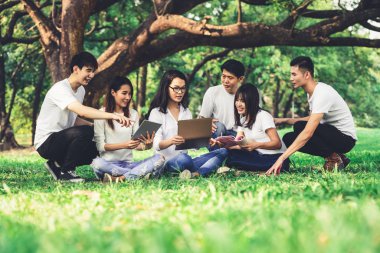Üniversite veya okul parkında grup projesinde okuyan genç öğrencilerden oluşan ekip. Mutlu öğrenme, topluluk takım çalışması ve gençlik arkadaşlık konsepti.