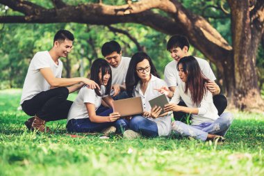 Üniversite veya okul parkında grup projesinde okuyan genç öğrencilerden oluşan ekip. Mutlu öğrenme, topluluk takım çalışması ve gençlik arkadaşlık konsepti.