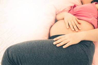 Mutlu hamile kadın dinlenme ve stres rahatlama için evde yatak odasında yatakta uyuyor. Hamile karnında bebek tutan genç anne bekliyor. Doğum öncesi bakım ve kadın gebelik kavramı.