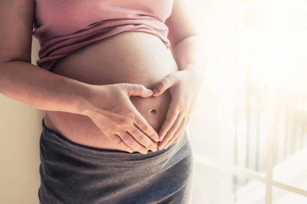 妊娠中の女性は 子供の世話をしながら自宅で幸せを感じています 妊娠中の腹に赤ちゃんを抱いている若い期待の母親 出産前ケアと女性妊娠概念 — ストック写真
