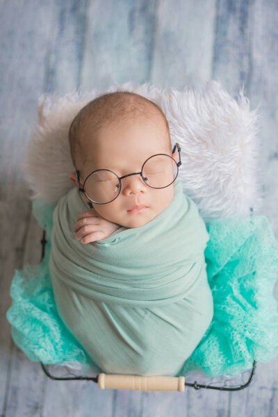 Adorable newborn baby sleeping in cozy room. Cute happy infant baby portrait with sleepy face in bed. 