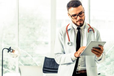 Hastanede tablet bilgisayar üzerinde çalışan doktor.