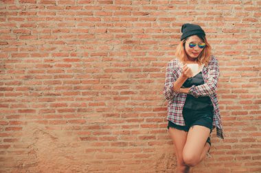 Mutlu genç kadın tuğla duvara karşı duran.