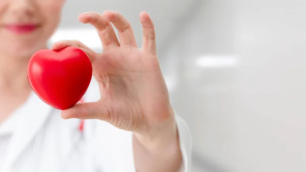 Médico segurando um coração vermelho no escritório do hospital . — Fotografia de Stock