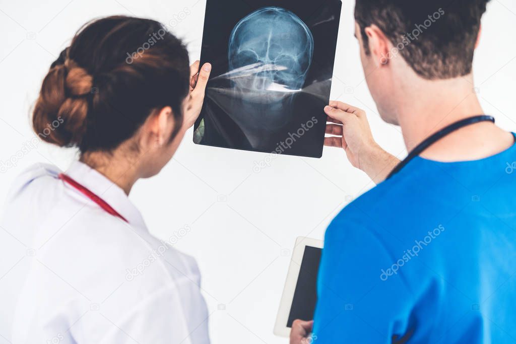 Doctors working with x ray film of patient head.